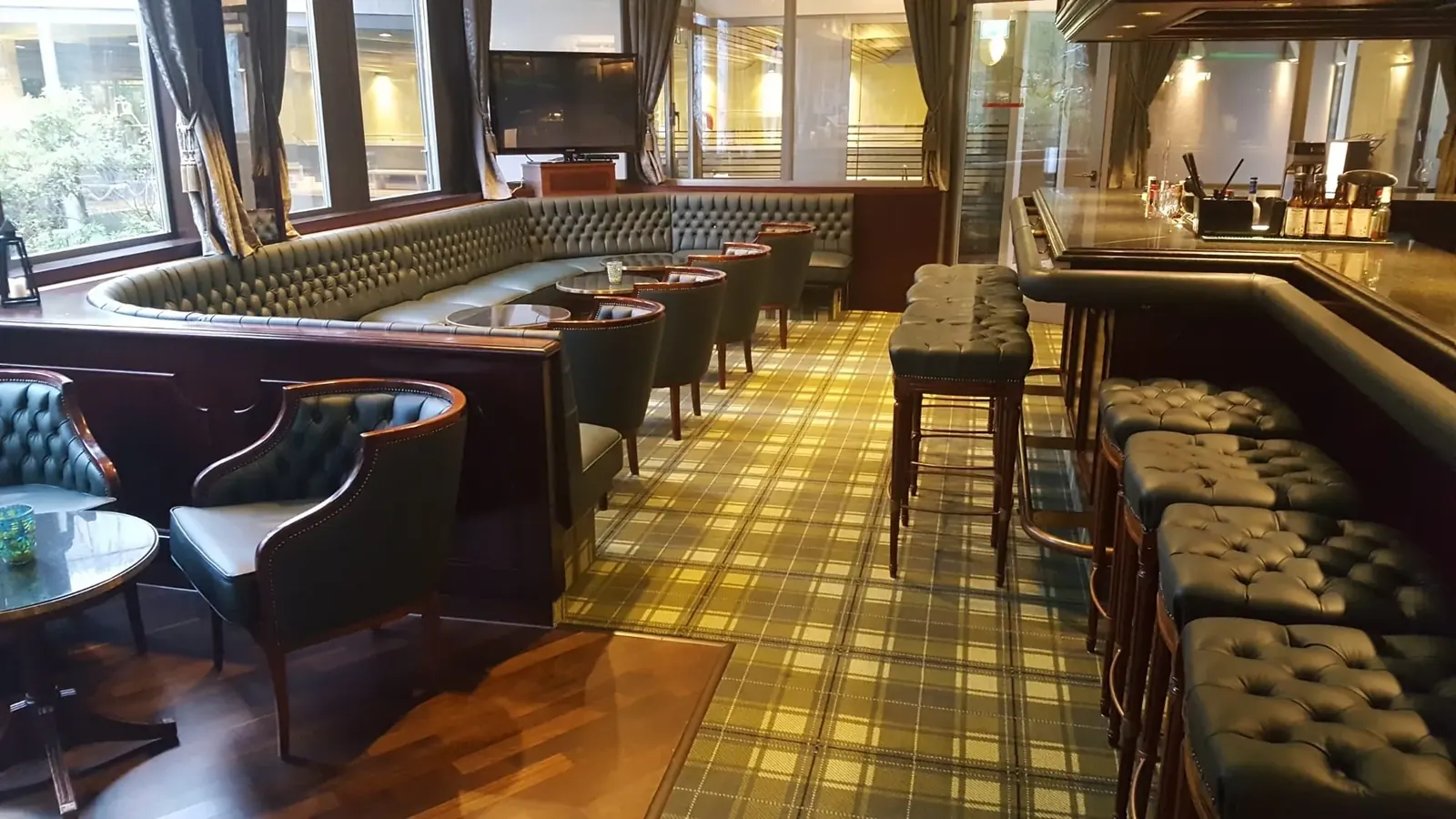 Lounge im Badischen Hof Baden-Baden mit Lederbänken und kariertem Teppich